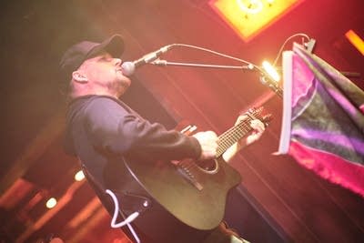 A musician sings and plays guitar onstage