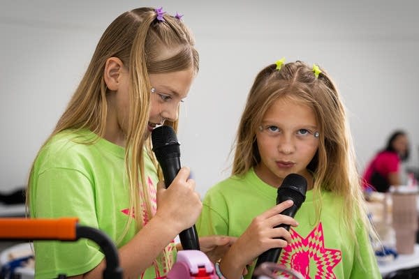 Two girls sing into mics