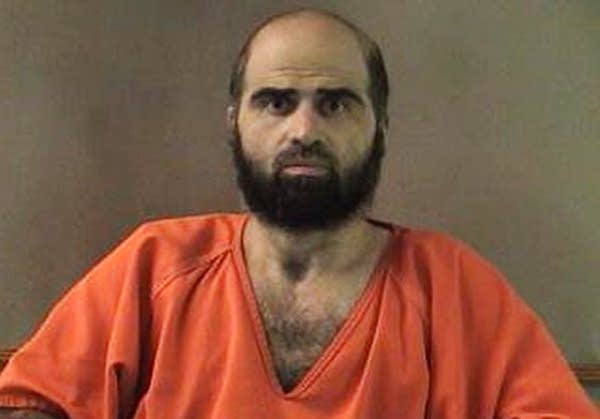 A grainy photo of a man in an orange prison jumpsuit.