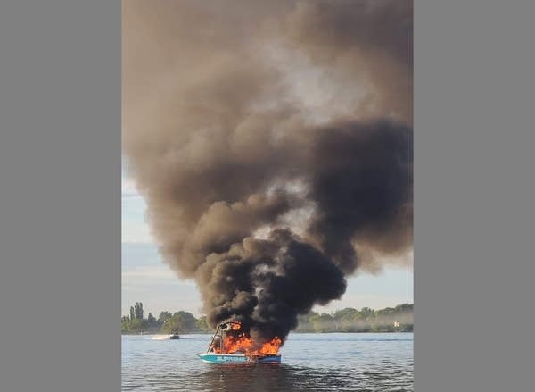 Photo of a boat completely on fire in a lake