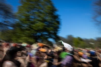 A winged puppet flies through a crowd
