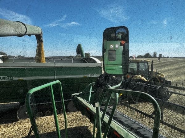 A combine unloads soybeans into a neighboring storage truck.