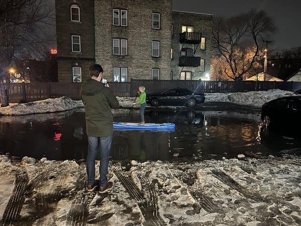 A woman paddleboards on a puddle