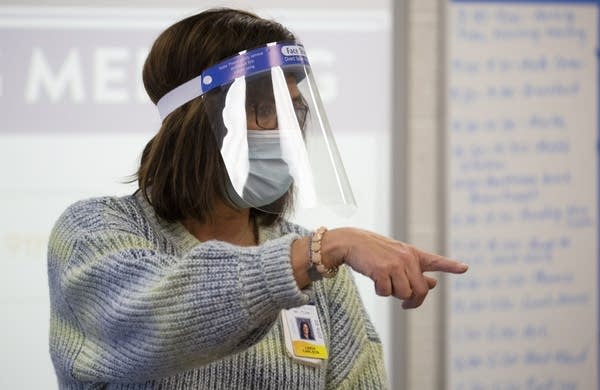 A teacher wearing a face shield and face mask.