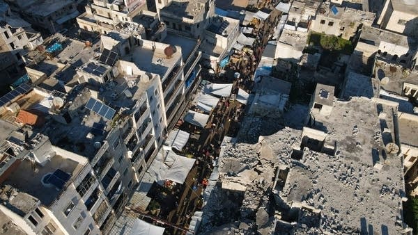 People shop in a market in Ariha near destroyed buildings in March.