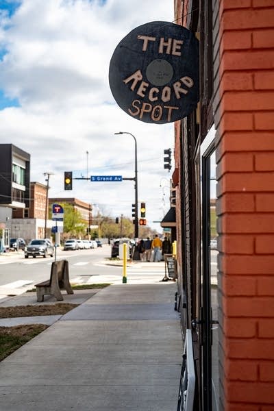 A circular (i.e. record-shaped) sign hangs from the facade of a record store