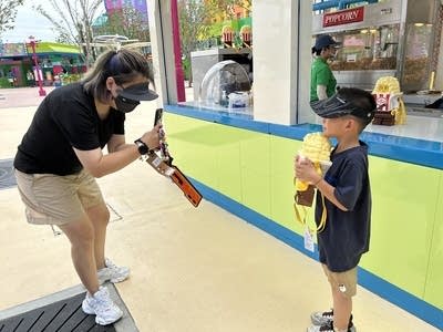 A mother takes a photo of her son holding a box of popcorn shaped like a Lego person at Legoland Shanghai