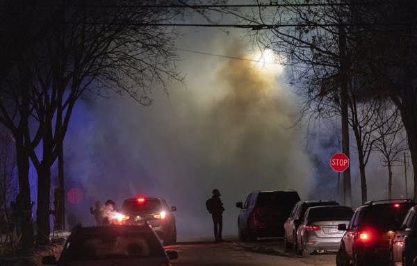 Smoke fills the night sky on a city street.