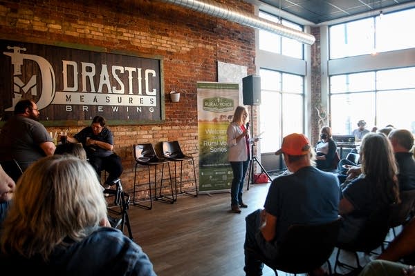 A woman speaks in front of an audience at a brewery.