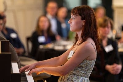 A musician plays organ in a room full of people seated at tables