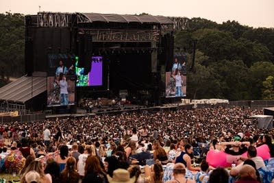 Remi Wolf performing on stage and giant crowd watching