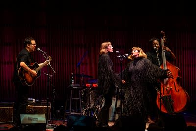 Four musicians performing together onstage in a concert hall