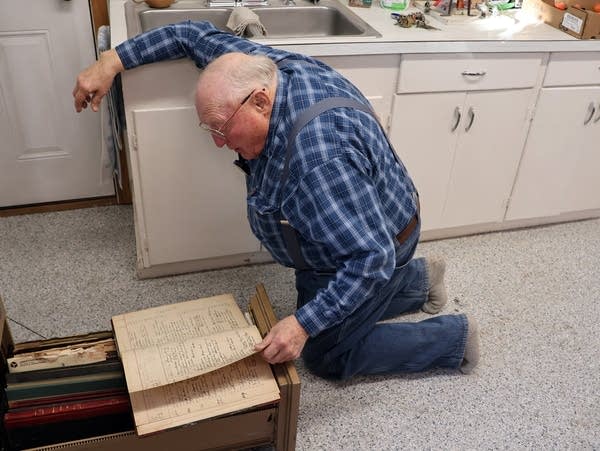 a man kneels on the floor looking at a book