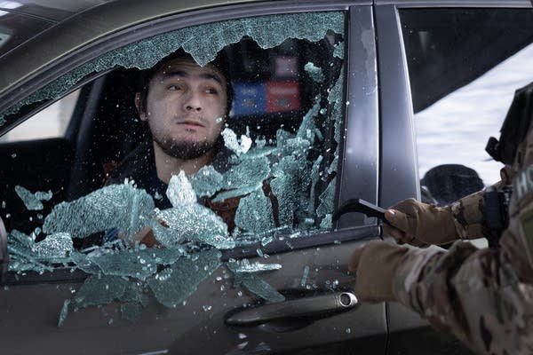 A man in his car with his windshield being broken