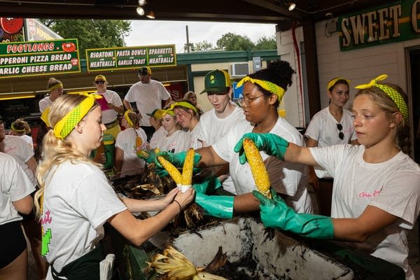 works shuck roasted corn at state fair