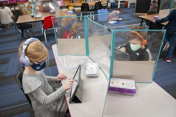 A students sits behind a barrier at a table. 