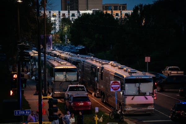 Several tour buses parked outside a stadium