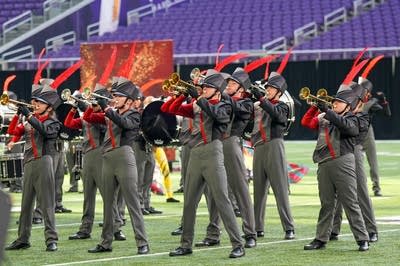 A marching band performs on the field of a football stadium.