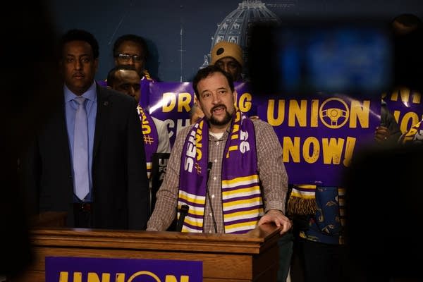 A man stands behind a podium during a press conference.