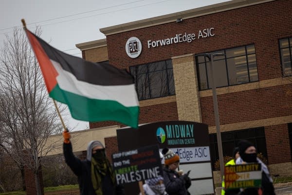 People wave flags and banners in front of a business park