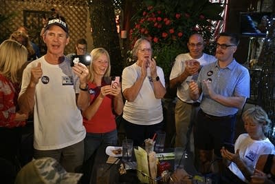 Political supporters take photos and clap at a watch party.