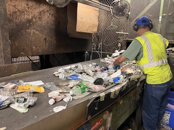 a man sorts recycling next to a conveyor belt