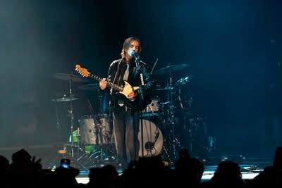 A musician sings and plays guitar onstage 
