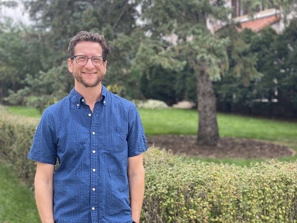 A man in a blue shirt stands outside