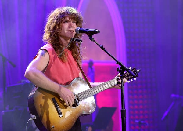 A musician sings and plays guitar onstage