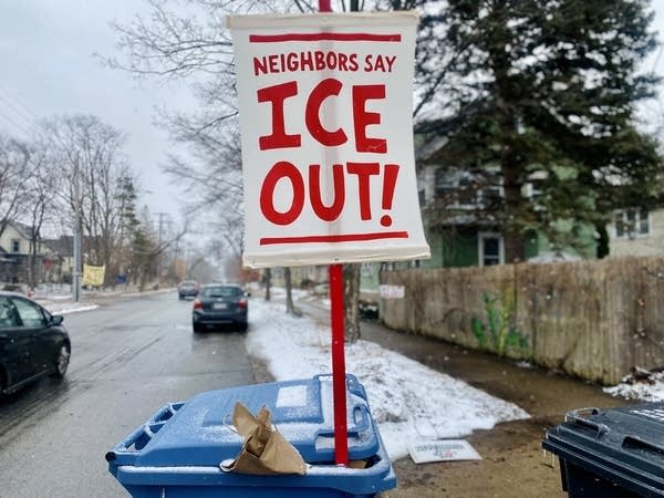A red and white sign reads "Neighbors Say ICE OUT!"