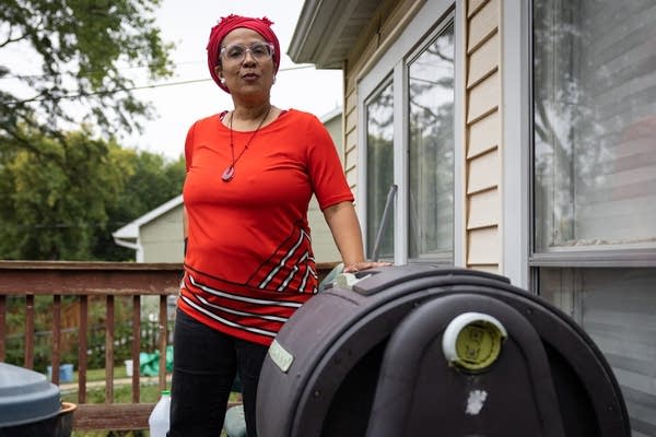 A woman rests her hand on a large compost bin