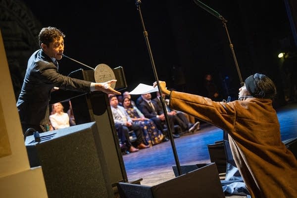 A woman hands a man a sheet of paper