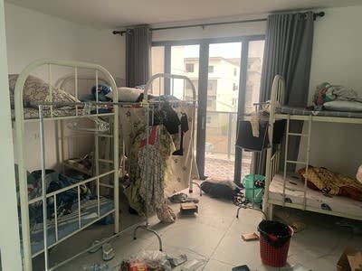A room with multiple bunk beds and clothes strewn about