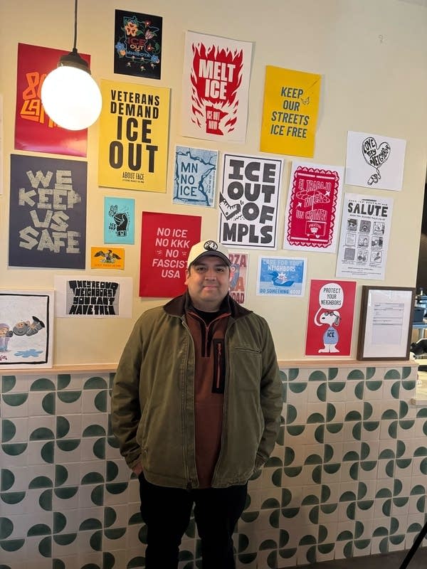 A man stands in front of a number of signs on display in a business.