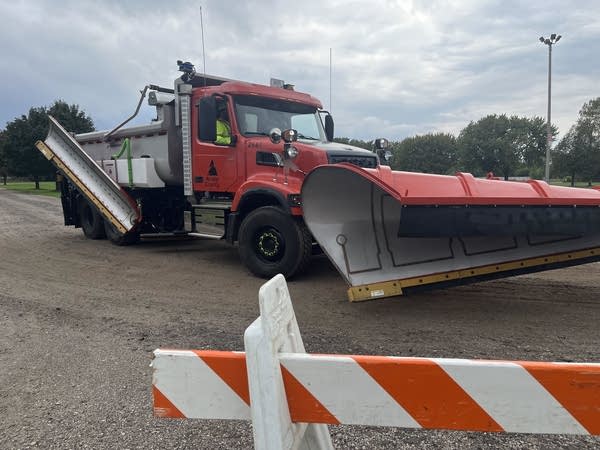 A plow truck drives by a caution barrier.
