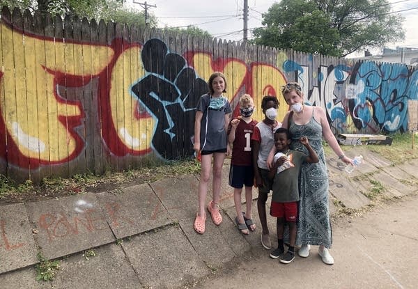 A transracial family poses in front of a wooden fence with graffiti art. 