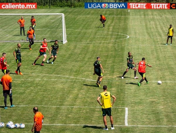 Football players practice on a playing field