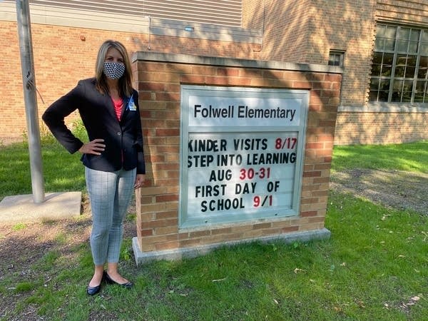 a woman stands next to an elementary school