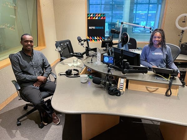a man and a woman smile in a broadcast studio