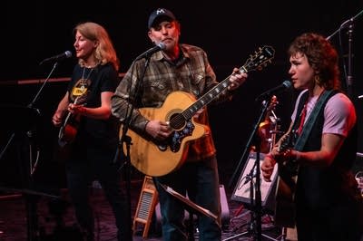 Three musicians perform onstage.