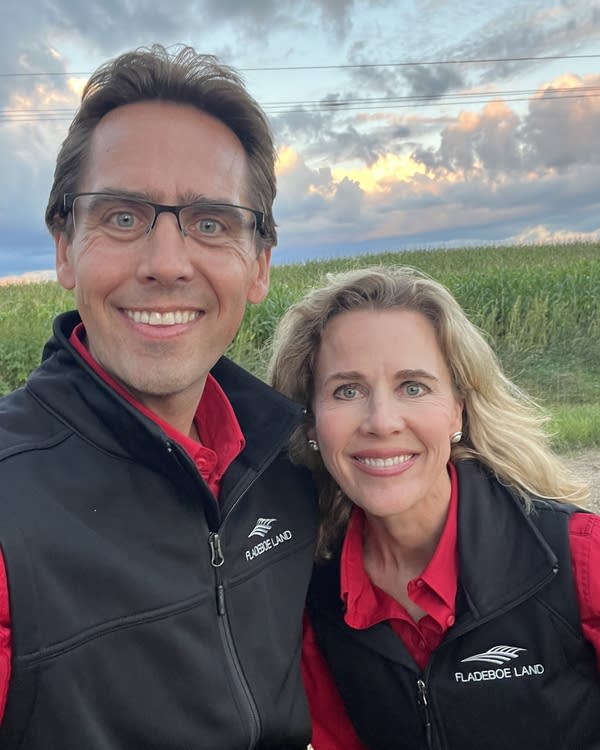 a man and a woman standing in front of a field