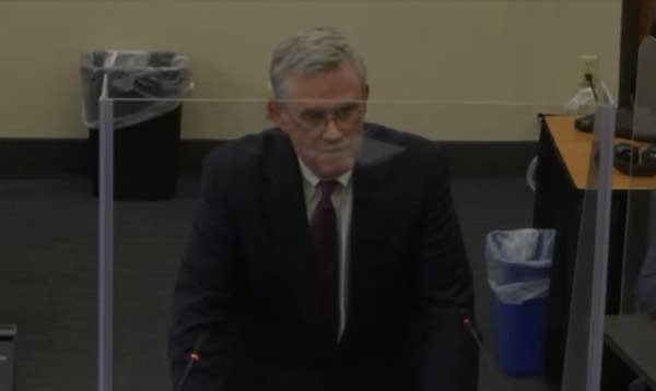 A man stands behind a desk