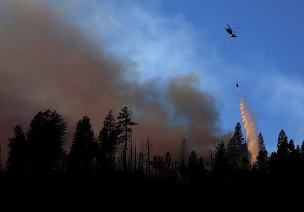 A helicopter drops water on the Camp Fire near Cresta, Calif.