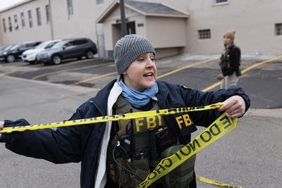 Law enforcement set up yellow caution tape around a business.