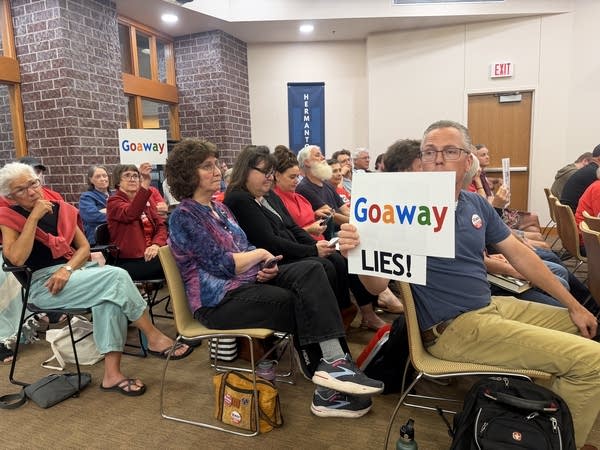 A man shows a sign at a meeting
