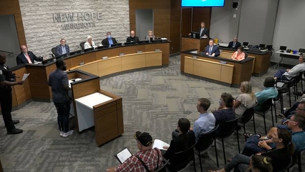 A man stands at a podium, addressing a city council.