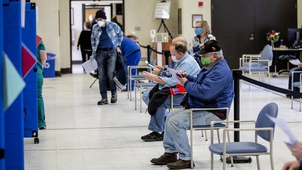 People sit at table and fill out paperwork.