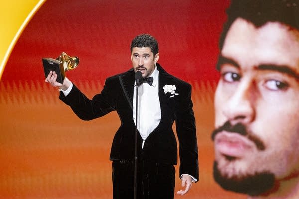 A man speaks while holding an award statuette he just won