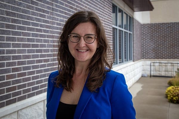 A woman in a blue blazer poses for a photo.