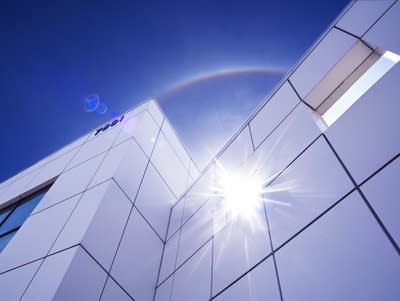 Sun reflects outside Paisley Park with blue sky above.